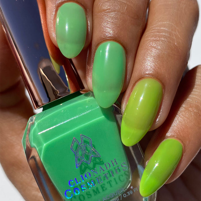 Close-up of nails painted with Thrilled Nail Lacquer on medium skin tone. Hand is holding polish bottle.