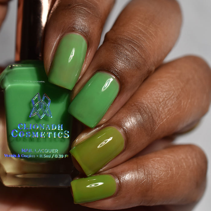 Close-up of nails painted with Thrilled Nail Lacquer on deep skin tone. Hand is holding polish bottle.