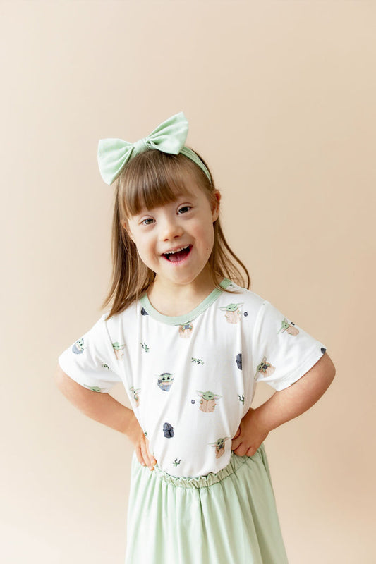 Young girl posing wearing the Toddler Basic Tee in Grogu™ with a light green skort