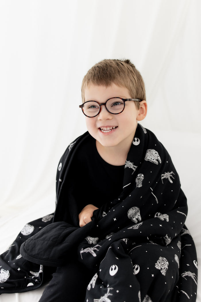 Close up of  a young boy with the Toddler Blanket in STAR WARS™ 1.0 wrapped around his shoulders