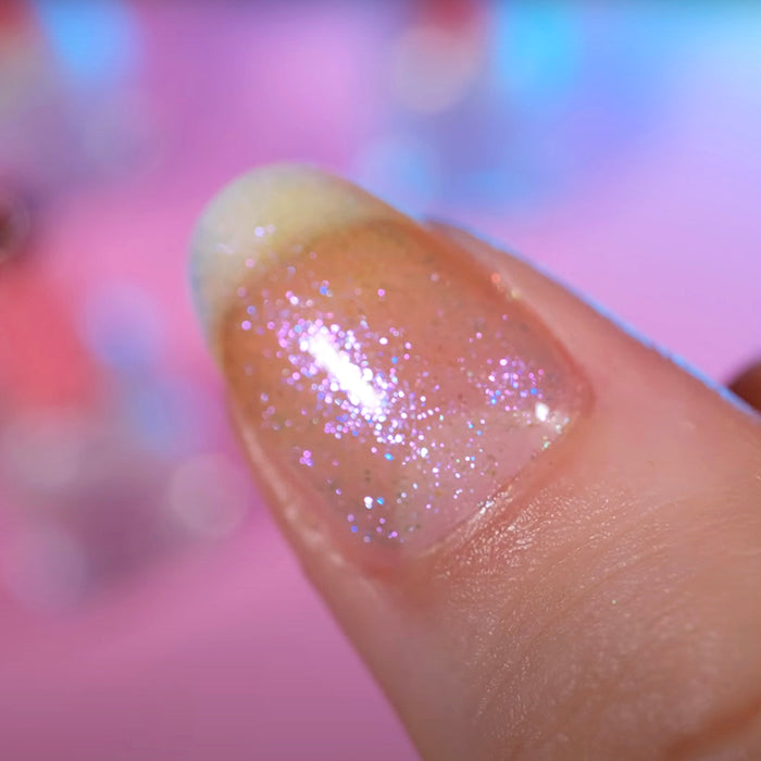 Close-up of one nail painted with Walking on Air Nail Lacquer on fair skin tone. Blurred pastel background.