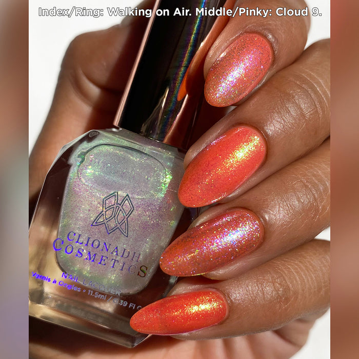 Close-up of nails painted with Walking on Air Nail Lacquer on medium skin tone. Hand is holding polish bottle.