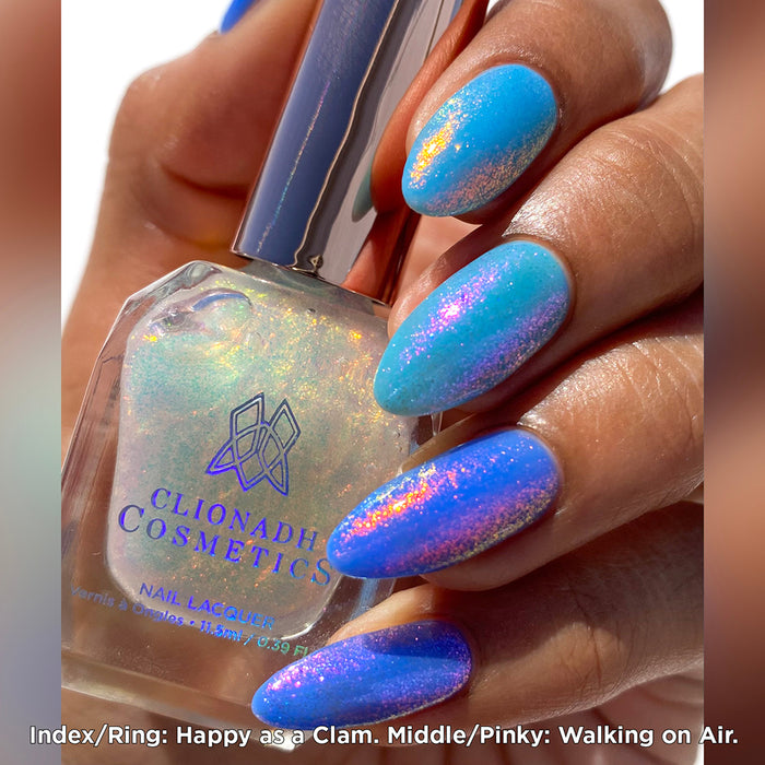Close-up of nails painted with Walking on Air Nail Lacquer on medium skin tone. Hand is holding polish bottle.