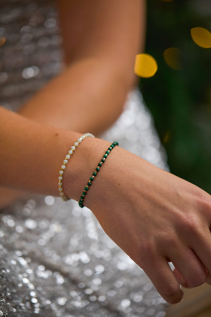 Close-up of a hand wearing two bracelets with a blurred background