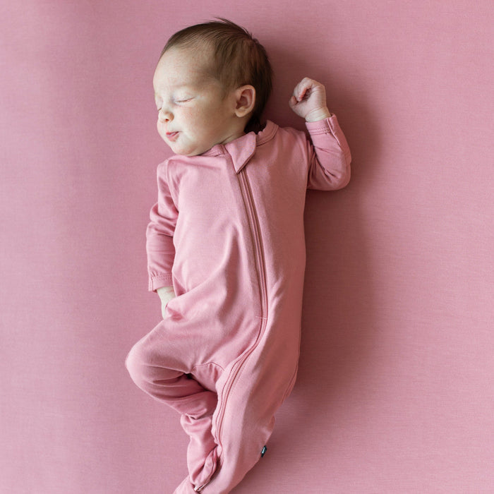 Newborn sleeping in Kyte Baby Zippered Footie in Apple Blossom